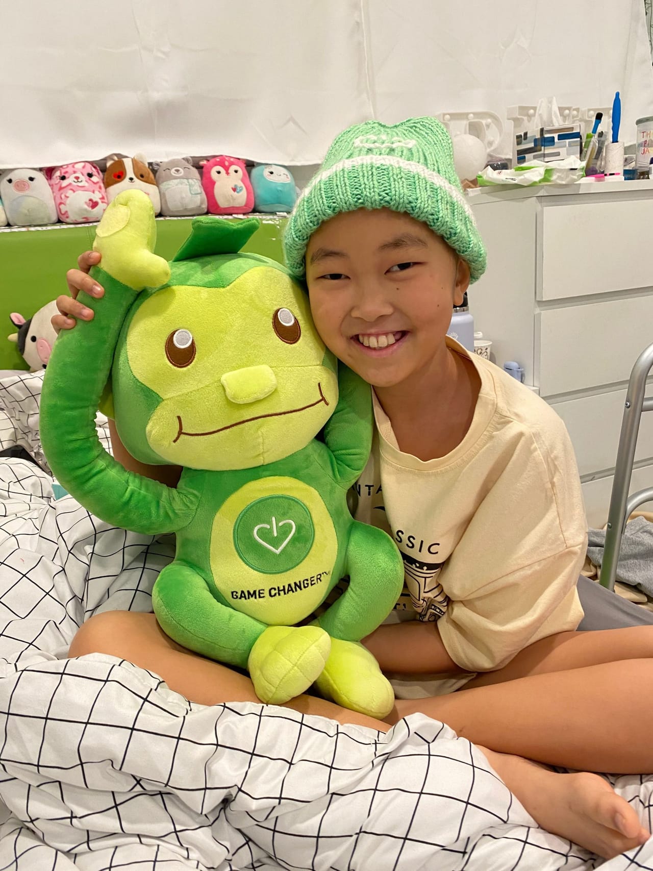 A young patient smiling with a stuffed monkey in a hospital game space